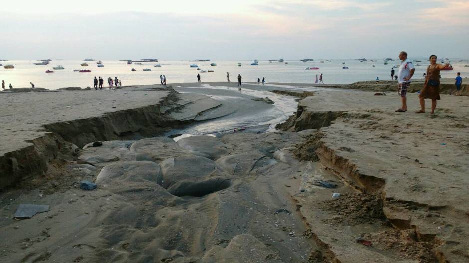 Urlauber betrachten die Zerstörungen, die das von der Beach Road abfließende Wasser am Strand hinterließ.