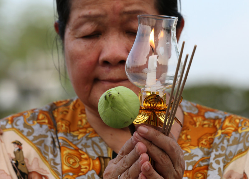 Mit einer Lotusblüte und einer brennenden Kerze in der Hand umrunden Buddhisten dreimal den Ubosot. Foto: epa/Narong Sangnak