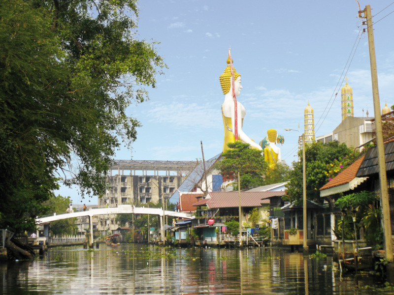 Das Bildnis eines stehenden Buddhas überragt den Kanal und dieses Stadtviertel in Thonburi.