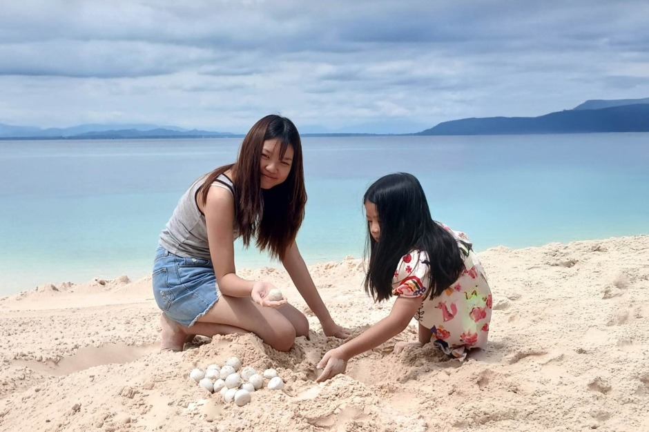 Zwei Mädchen legen am Strand vorsichtig frisch abgelegte Schildkröteneier frei und erhalten so Einblick in ein Schutzprojekt, das den natürlichen Fortpflanzungszyklus begleitet. Foto: Tourism Authority Of Thailand