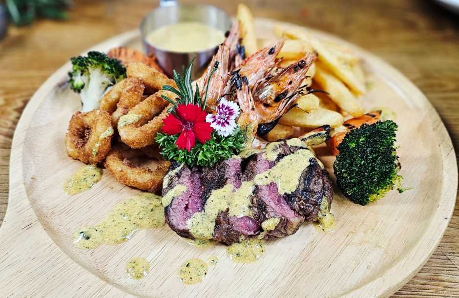 Surf & Turf mit australischem Rindsmedaillon, Garnelen, knusprigen Calamari, Pommes frites und Gemüse.
