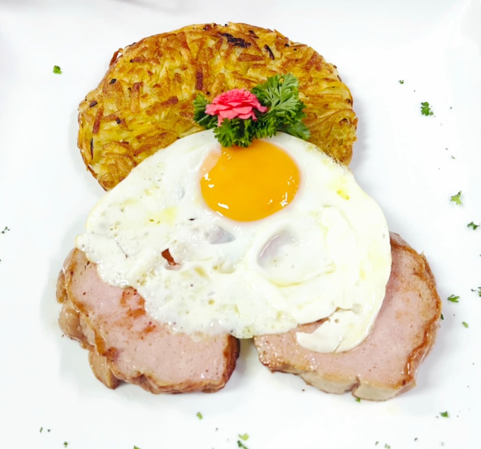 Goldbraun gebratener Fleischkäse mit knusprigem Rösti und Spiegelei – ein Schweizer Klassiker.