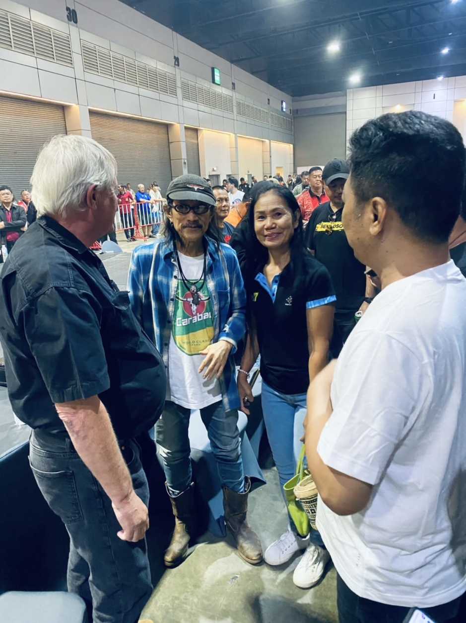 Adrian Aegerter (l.) und Sek Loso (r.) begrüßen Rocklegende Aed Carabao während der Ausstellung in Muang Thong Thani. Foto: Aegerter