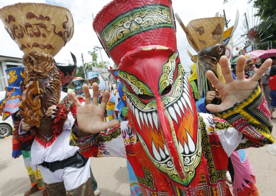 Teilnehmer des Phi-Ta-Khon-Festivals ziehen mit kunstvollen Geistermasken und farbenfrohen Kostümen durch die Straßen von Dan Sai in der Isaan-Provinz Loei.