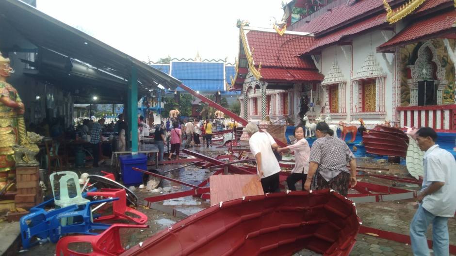 Nach dem Sturm räumen Anwohner Trümmerteile auf dem Gelände einer Tempelanlage im Bezirk Phrao beiseite, während beschädigte Konstruktionen im Hintergrund liegen. Bild: PR Chiangmai