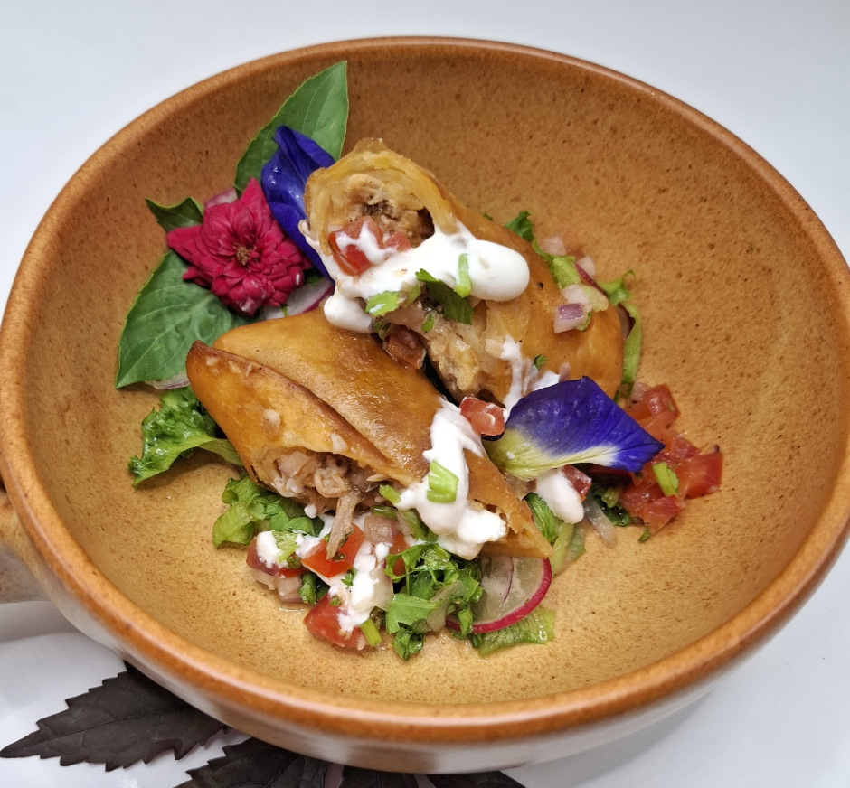 Die „Pulled Pork Flautas“ werden auf Salat mit frischer Tomatensalsa angerichtet.