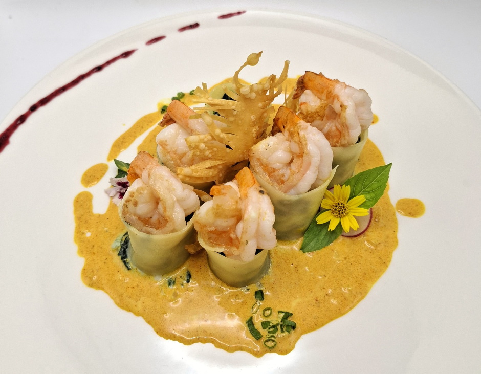 Cannelloni mit Garnelen und Spinat in milder Currysauce, angerichtet mit knusprigen Garnelen und feinen Kräutern.