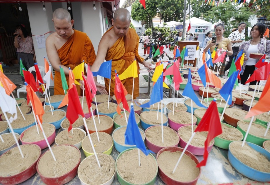 Buddhistische Mönche und Gläubige gestalten Sand-Chedis, die im Rahmen der Feierlichkeiten mit Fahnen und Blumen geschmückt werden. Bild: epa/Rungroj Yongrit