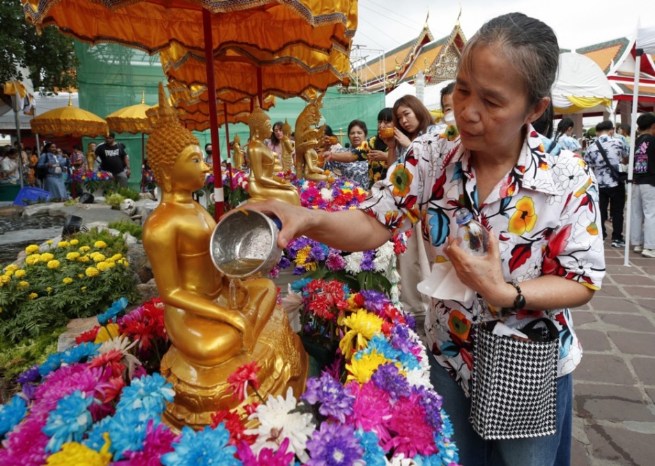 Eine Frau übergießt eine Buddha-Statue mit Wasser und nimmt damit an einem zentralen Reinigungsritual des Songkran-Festes teil. Bild: epa/Rungroj Yongrit