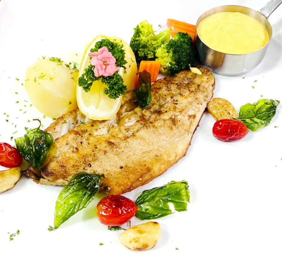 Gebratenes Wolfsbarschfilet mit Sauce Hollandaise, Salzkartoffeln und frischem Buttergemüse.
