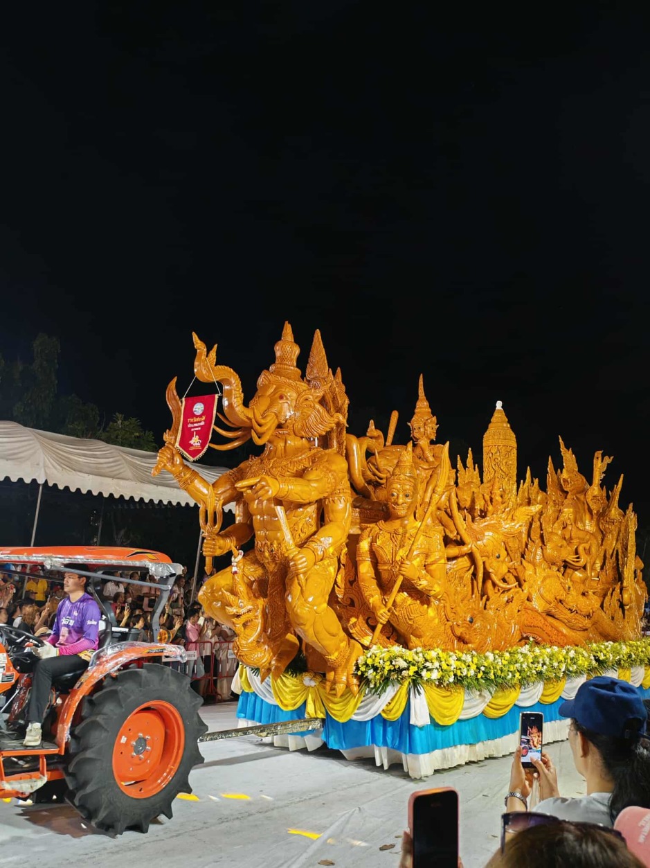 Ein monumentaler Kerzenwagen mit vielarmiger Götterfigur zieht während der Prozession durch die Straßen von Ubon Ratchathani und zieht zahlreiche Zuschauer an.
