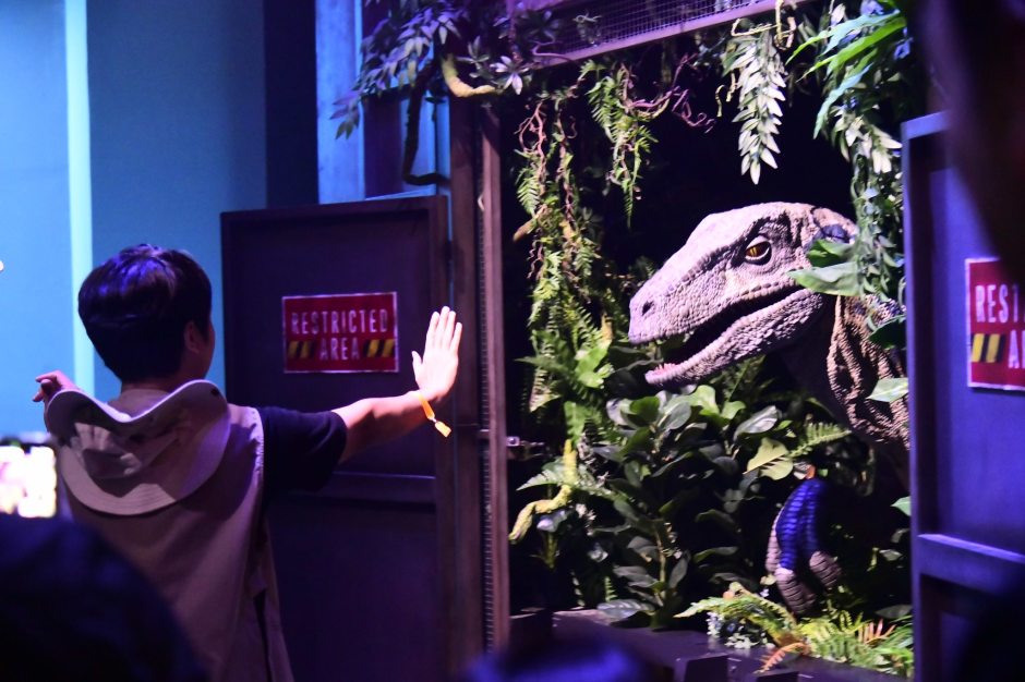 Ein Besucher interagiert hautnah mit einem Velociraptor in der Jurassic World Ausstellung in Bangkok. Foto: Bangkok Metropolitan Administration