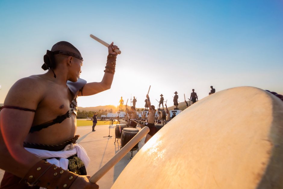 Traditionelle Trommel- und Kampfperformance vor historischer Kulisse.