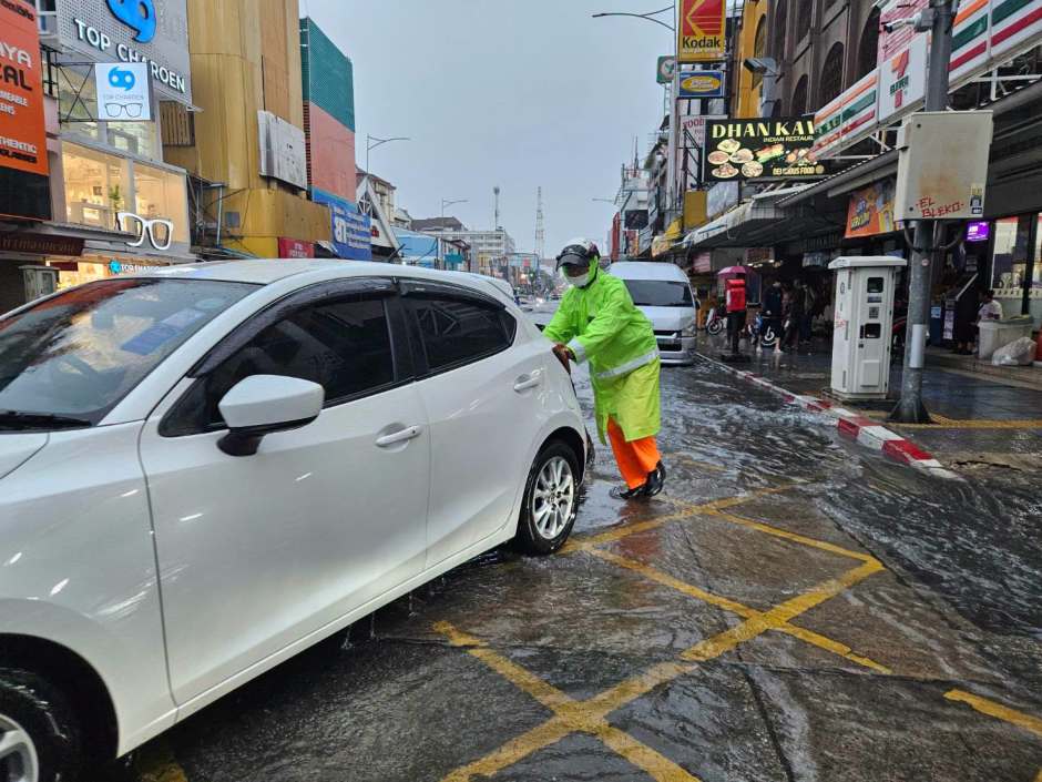 Ein im Hochwasser liegengebliebener Pkw wird von einem Einsatzhelfer aus dem Gefahrenbereich geschoben. Foto: Pattaya City Police
