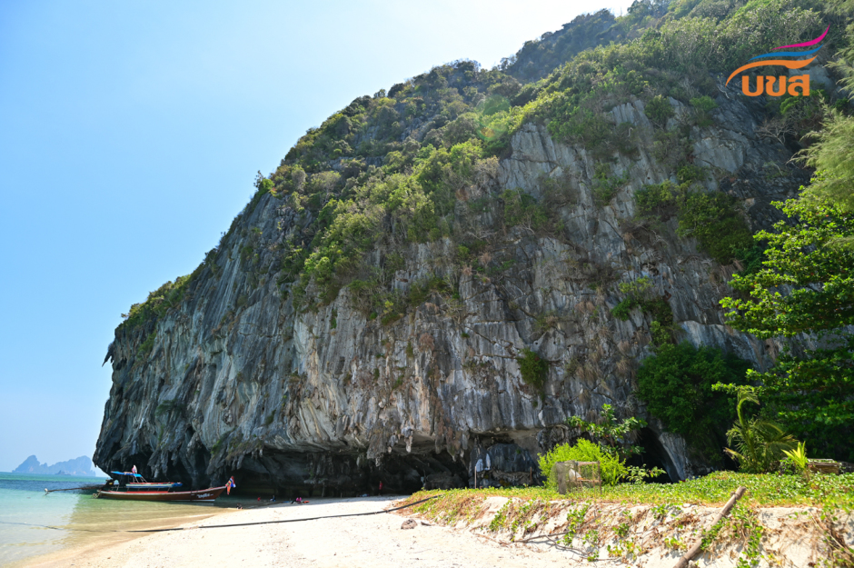 Steile Kalksteinfelsen prägen die Küste der Insel Lao Liang Phi im Mu-Ko-Petra-Nationalpark in der Provinz Trang, wo kleine Boote am hellen Sandstrand anlegen. Foto. The Transport Co.